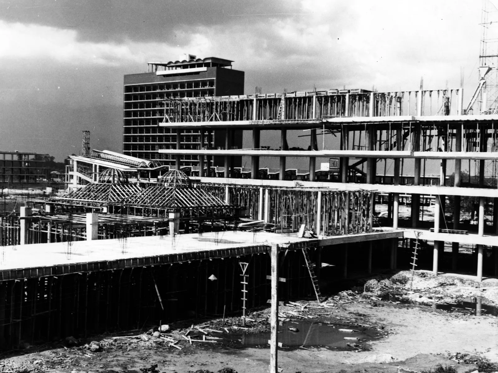 Ciudad Universitaria under construction: concrete slabs and columns in progress, with the completed Torre de Ciencias in the background.